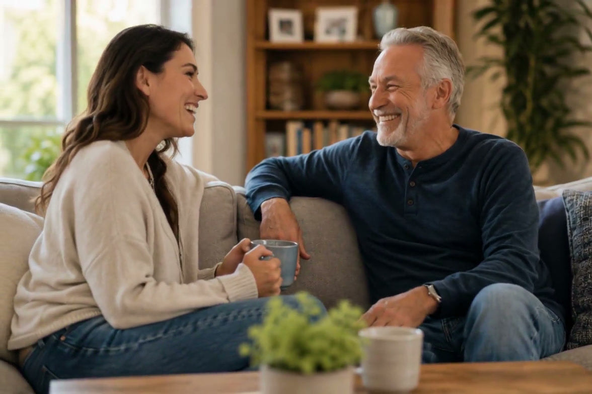A daughter and her father laughing together on the sofa